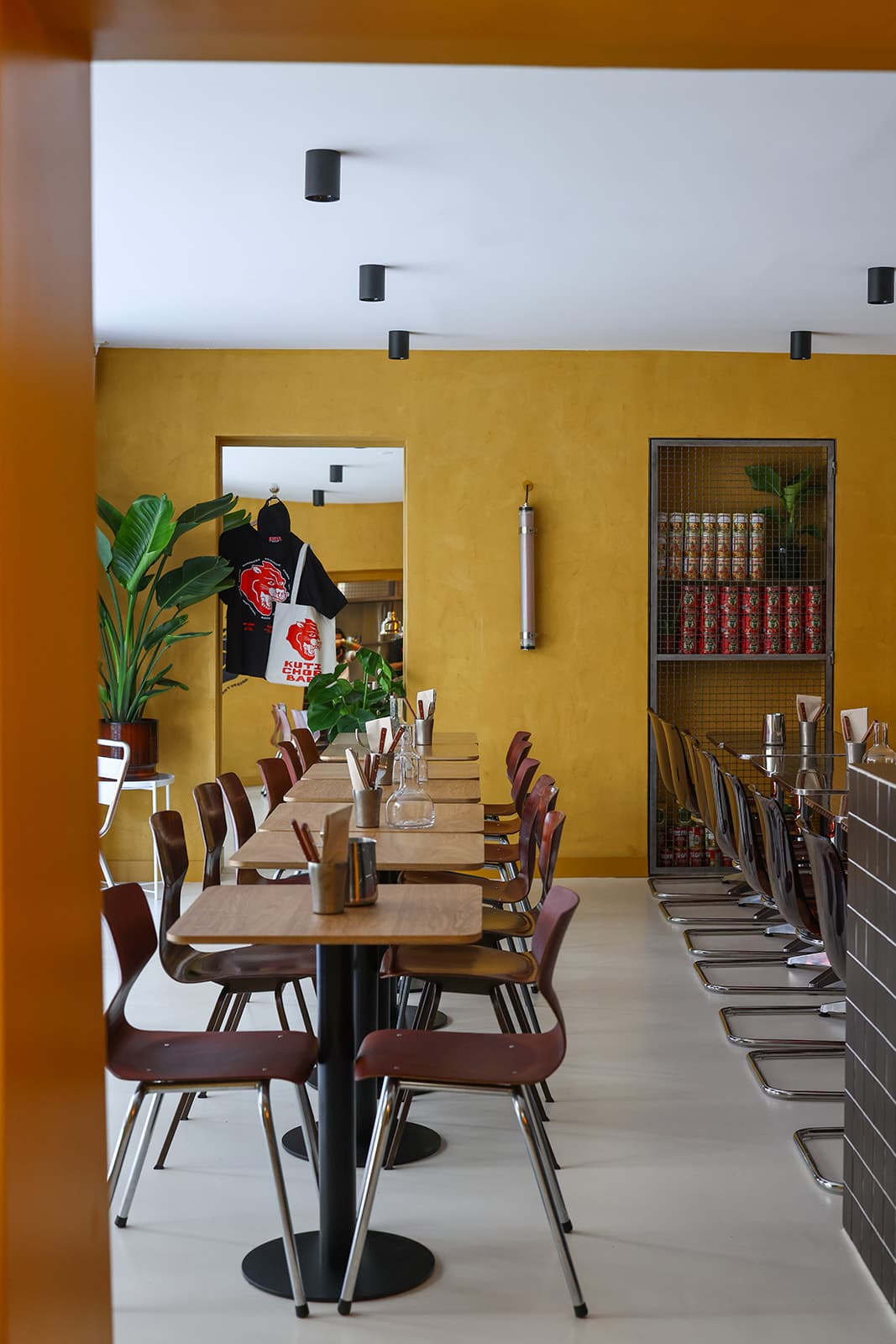 Salle du chop bar KUTI : murs ocre, tables en bois dépareillées et bar en carrelage
